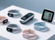 Professional overhead shot of NFC wristbands arranged on a clean white surface beside an industrial handheld RFID scanner and digital temperature/humidity display
