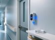 Professional interior of UK care home corridor with discreet RFID reader mounted near exit door and silicone RFID wristband on shelf