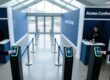 Professional overhead shot of NFC wristbands being scanned at a modern UK event entrance with streamlined queue lanes and digital signage