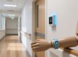 Professional interior of UK care home corridor with discreet RFID reader module mounted above doorway and RFID wristband on mannequin wrist