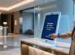 Luxury hotel guest tapping NFC wristband at digital check-in kiosk in modern lobby