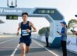 Marathon runner wearing RFID fabric wristband crossing finish line with timing equipment in background