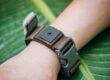 Eco-friendly reusable RFID silicone wristbands on wooden table with green leaves, sustainability concept