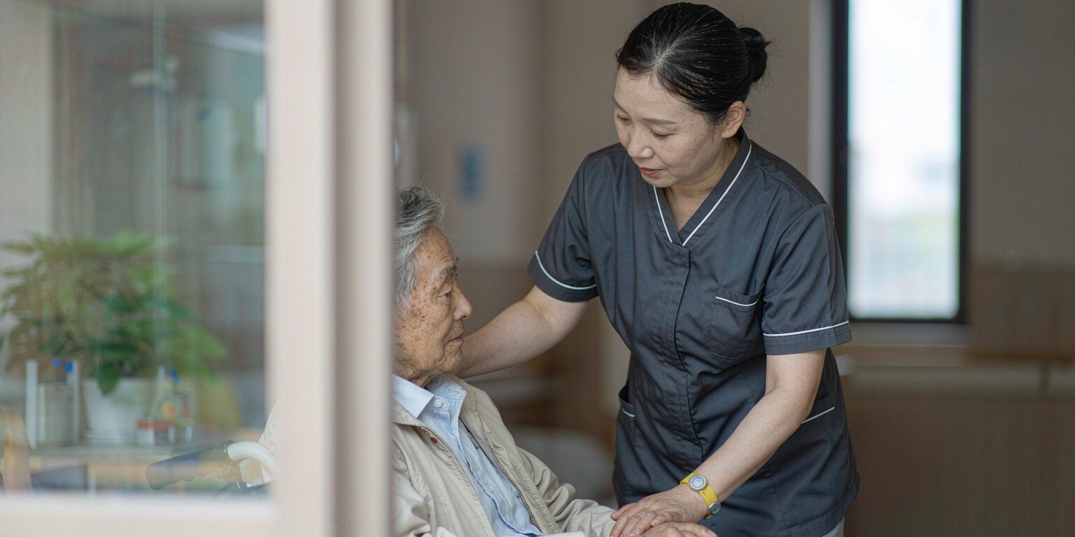 Elderly Japanese patient wearing RFID wristband while nurse scans with handheld reader in modern care facility
